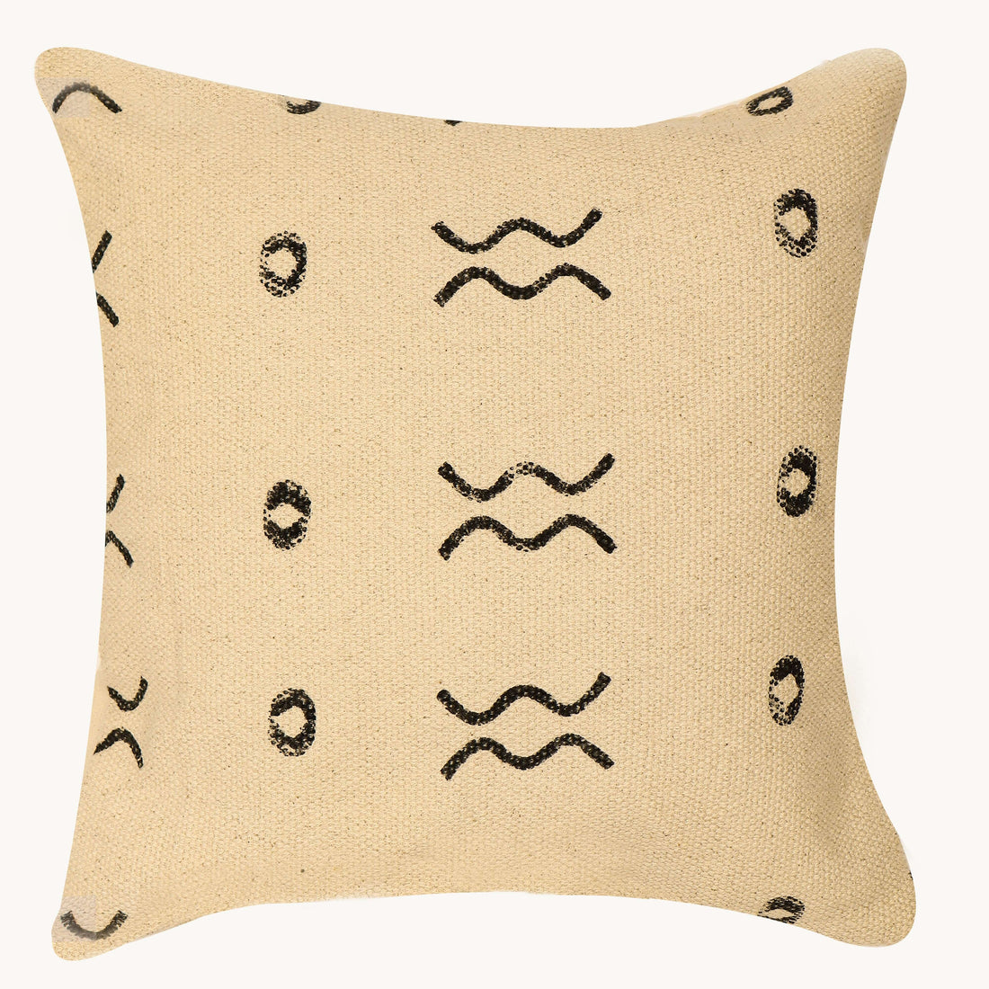 A cushion cover with a block print design displayed on a chair in a room with wooden flooring and white curtains.