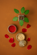 Decorative setting with red powder, nuts, and green leaves on an orange background.