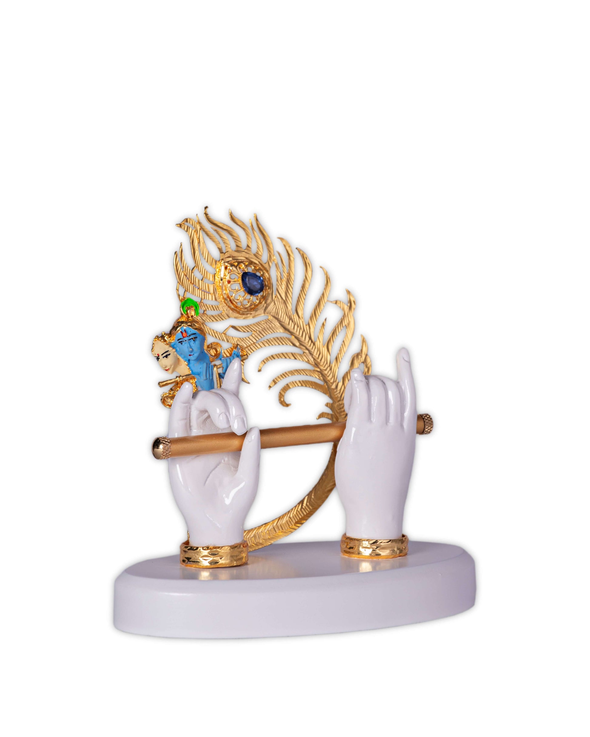 A decorative idol of Lord Krishna showcasing white hands holding a golden flute, adorned with a golden peacock feather, and featuring a small blue Krishna figure playing the flute on a white base.