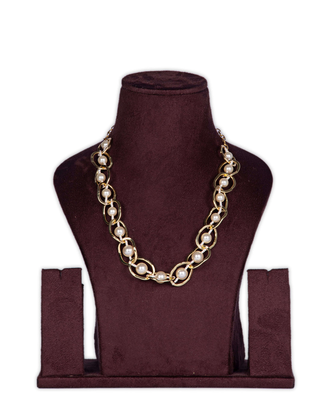 A handwrapped statement necklace with circular crystal beads in brown and beige colors, displayed on a plush white surface next to a wooden box and floral arrangement.