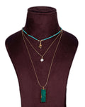 A display of layered necklaces with a prominent green agate pendant as the focus, set on a mannequin bust.