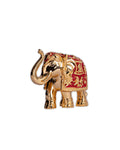 A gold-plated resin elephant show piece with red detailing, placed against a purple background with decorative elements around it.