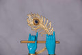 A striking sculpture featuring two blue hands, emblematic of Lord Krishna, holding a golden flute, with a majestic golden peacock feather adorned with a prominent blue gem positioned behind them.