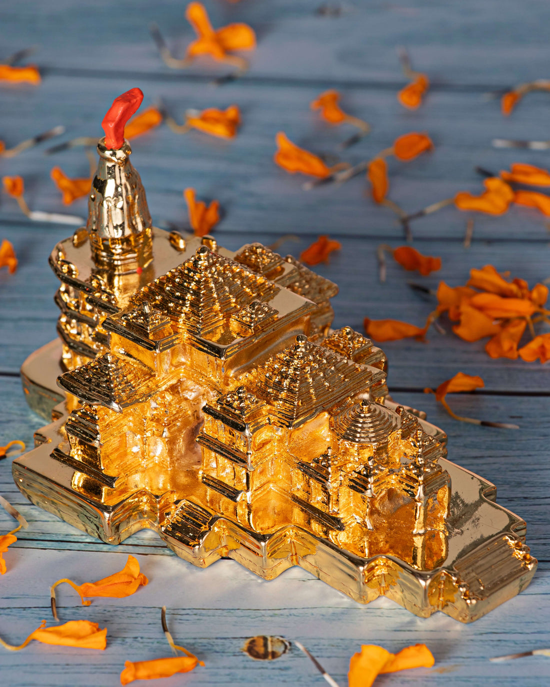 Ayodhya Ram Mandir idol without a base, held in hands, with rose petals scattered on a rustic wooden surface in the background.