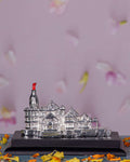 A silver-plated 3D model of the Ayodhya Ram Mandir, complete with intricate architectural details, a distinct red flag at its pinnacle, and presented on a dark, stable base.