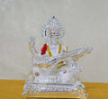 Silver-plated idol of Goddess Saraswati seated and playing the veena, with accents of red and gold on her attire.