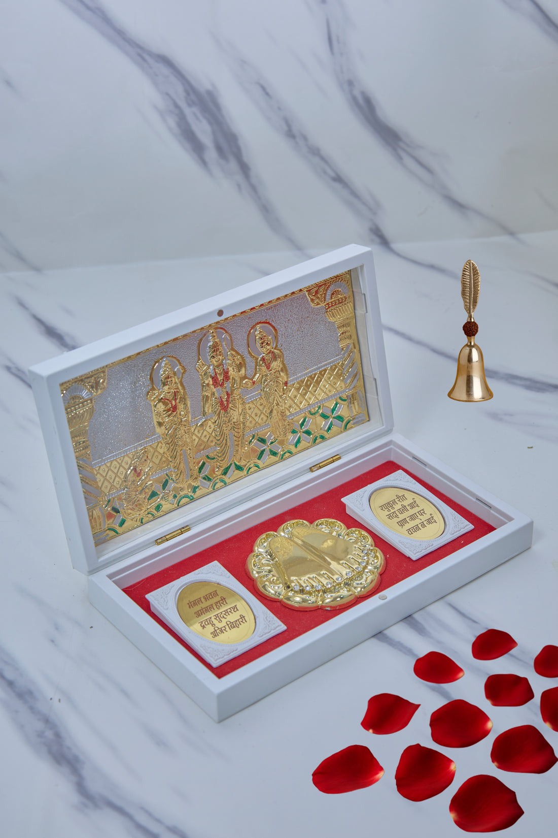 A white box open to reveal a gold-plated Ram Darbar tableau inside, featuring Lord Rama, Sita, Lakshmana, and Hanuman, alongside golden religious coins on a red velvet base.