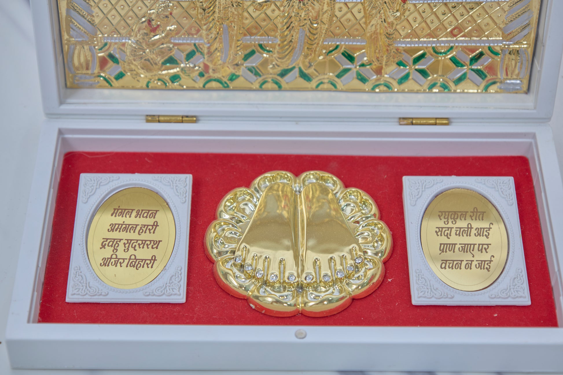 A white Ram Darbar Pocket Temple box open to reveal golden Lord Rama Charan Padukas (footprints) in the center, flanked by plates with sacred Sanskrit shlokas, and a golden embossed Ram Darbar scene on the inside of the lid