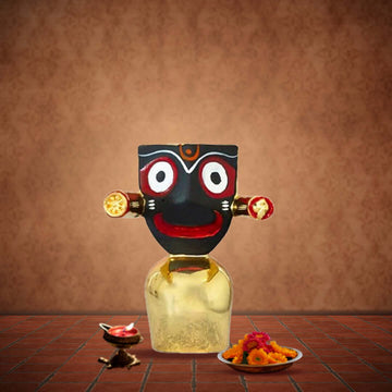 A photograph of a Jagannath Idol, which is 4 inches tall, placed on a golden base with a serene countenance and intricate detailing, against a plain backdrop.