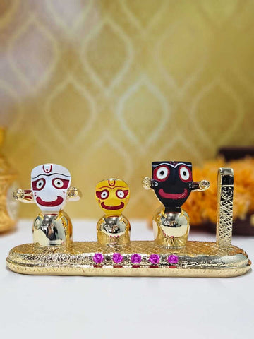 Three gold-plated idols of Lord Jagannath, Lord Balabhadra, and Goddess Subhadra, distinctively depicted with large round eyes and simplified forms, standing side by side on a golden base