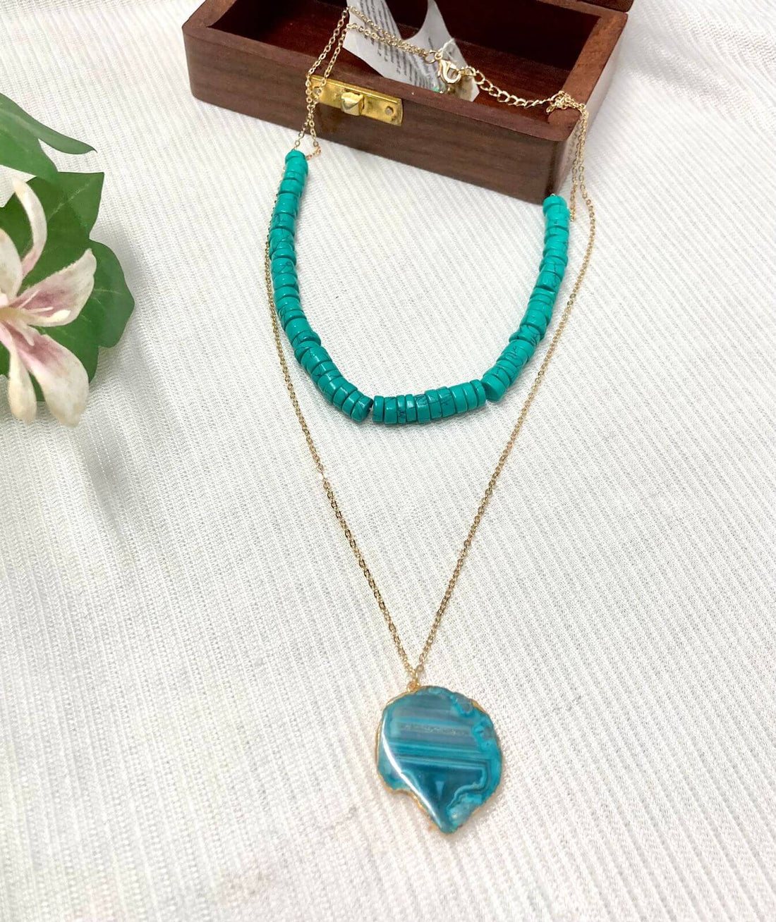 Aqua semi-precious agate stone necklace with a light gold finish displayed on a mannequin bust.