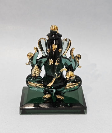 A crystal finish statue of Ganesh, the Hindu deity, with a green and gold color scheme, sitting on a square base.