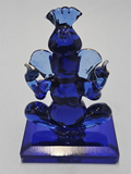 A blue glass statue of the Hindu deity Ganesha, shown seated on a rectangular base.
