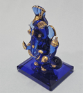 A blue crystal Ganesha idol with gold accents is shown, wearing a pagri. The statue is measured at approximately 2 inches wide and 3 inches tall, and it is displayed against a white background.