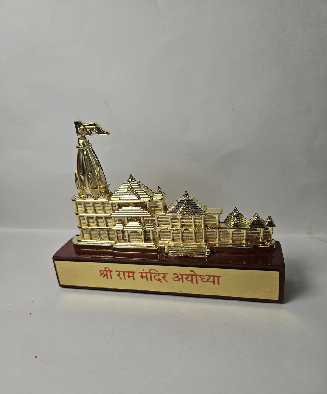Golden replica of the intricately designed Shree Ram Mandir (Ayodhya) temple model, sitting on a red base with the text "श्री राम मंदिर अयोध्या" in Hindi.