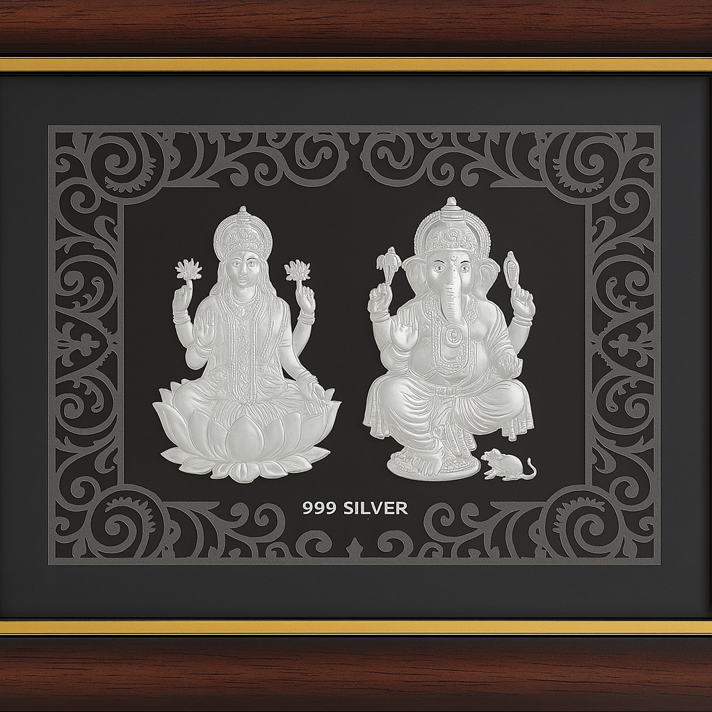 A brown framed silver relief featuring Hindu deities Lakshmi seated on a lotus on the left, and Ganesha seated with his vahana mouse on the right, with '999 SILVER' inscribed below them.