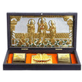 A gold-plated Ram Darbar pocket temple in a dark wooden box, featuring intricately detailed figures of Lord Rama, Sita, Lakshmana, and Hanuman, alongside golden Charan Padukas. The box is open, revealing the deities set against a silver and gold backdrop, and text in Hindi on plaques within the lid.