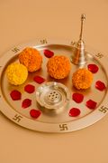 Decorative tray with marigold flowers and sweet balls on a neutral background.