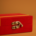 Close-up of a red jewelry box with a gold clasp on an orange background.