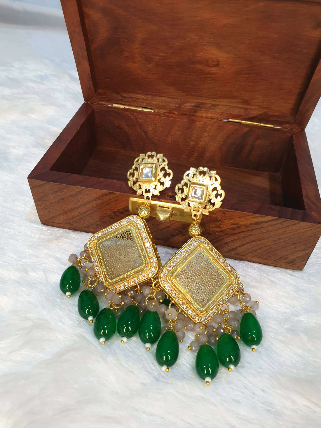 A long beaded necklace with pearl adornments and a unique pendant design, displayed alongside a wooden box.