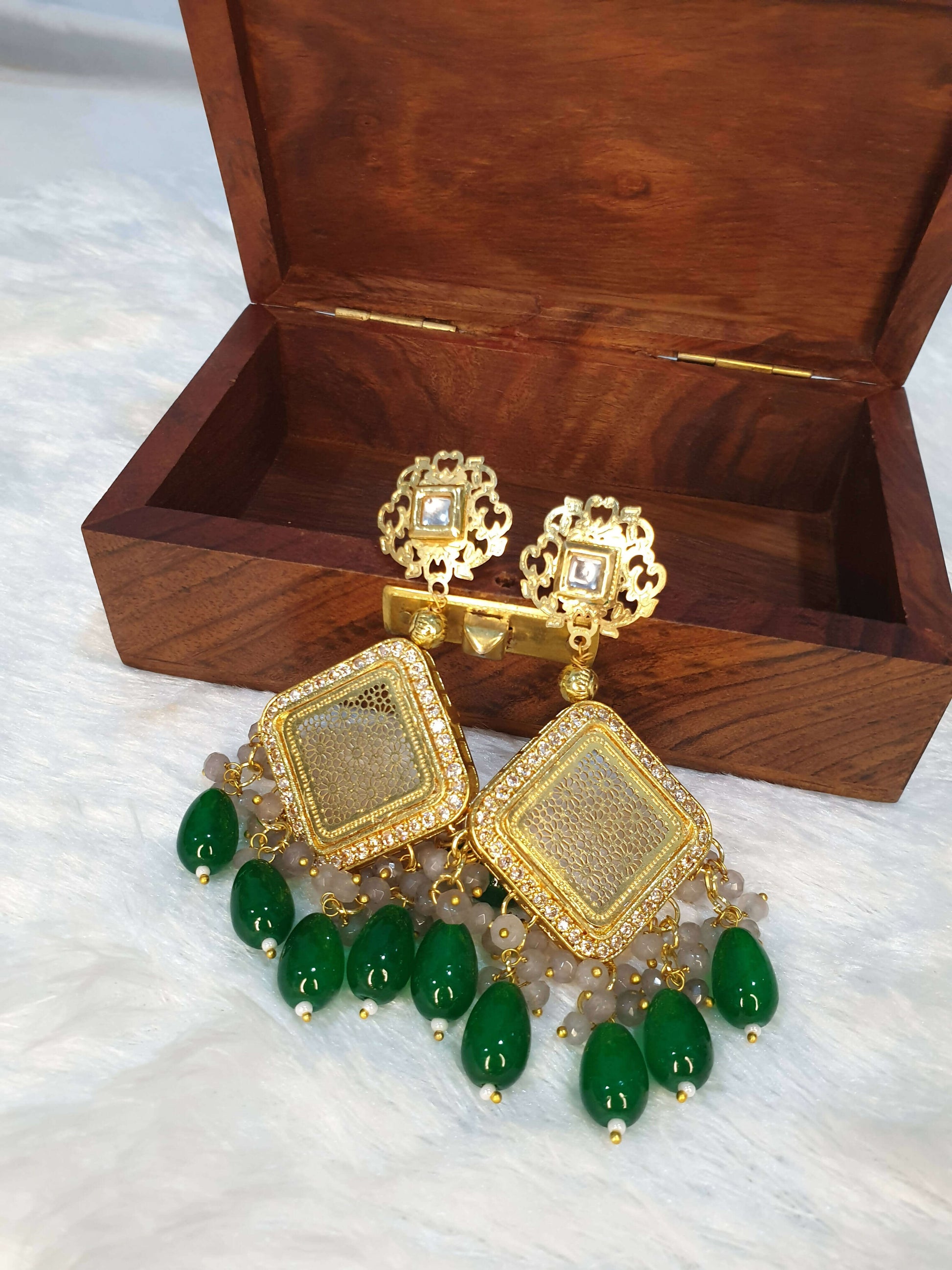 A long beaded necklace with pearl adornments and a unique pendant design, displayed alongside a wooden box.