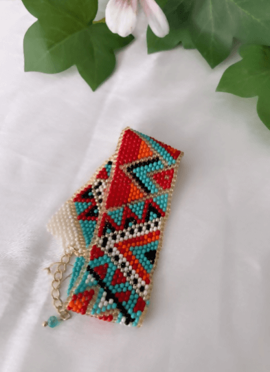 A colorful beaded bracelet on a person's wrist, featuring a vibrant palette with various colored beads and a gold-tone charm.