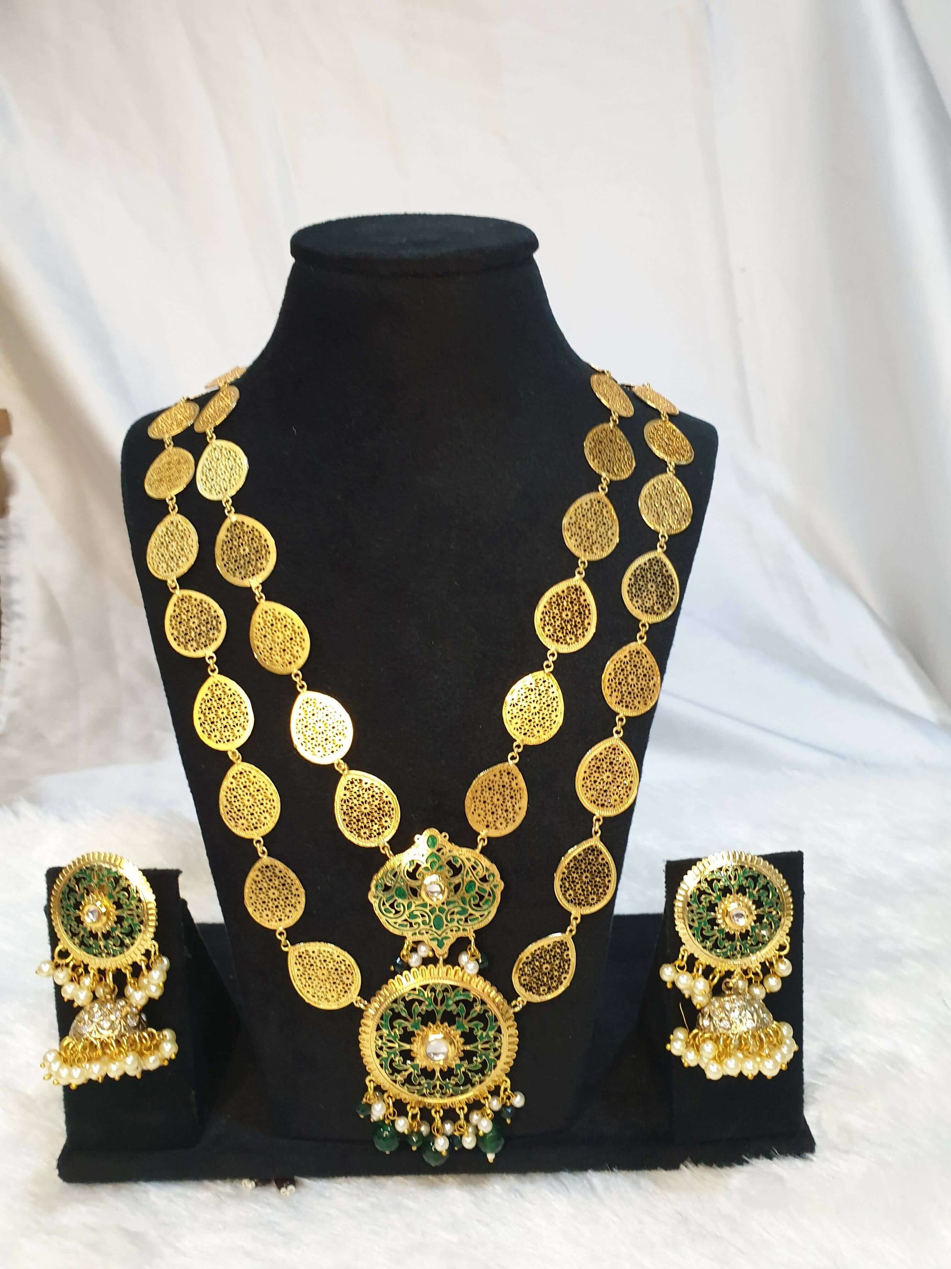 A gold-colored double layered filigree petals necklace accompanied by matching earrings on the black showpiece.