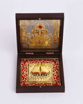 An open, brown wooden Pooja Box featuring a golden relief of Lord Ganesha with a red stone on the inside of the lid. The base of the box contains a square golden Charan Paduka (sacred footprints) set against a red fabric background with a decorative gold pattern. The keyword 'Golden Lord Ganesha - Charan Paduka Brown Box' captures the essence of the items within the box.