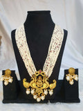 A display of traditional Indian jewelry, featuring a multi-string pearl haram with a gold-colored Lakshmi pendant, along with matching earrings with gold accents and pearls on the black showpiece.