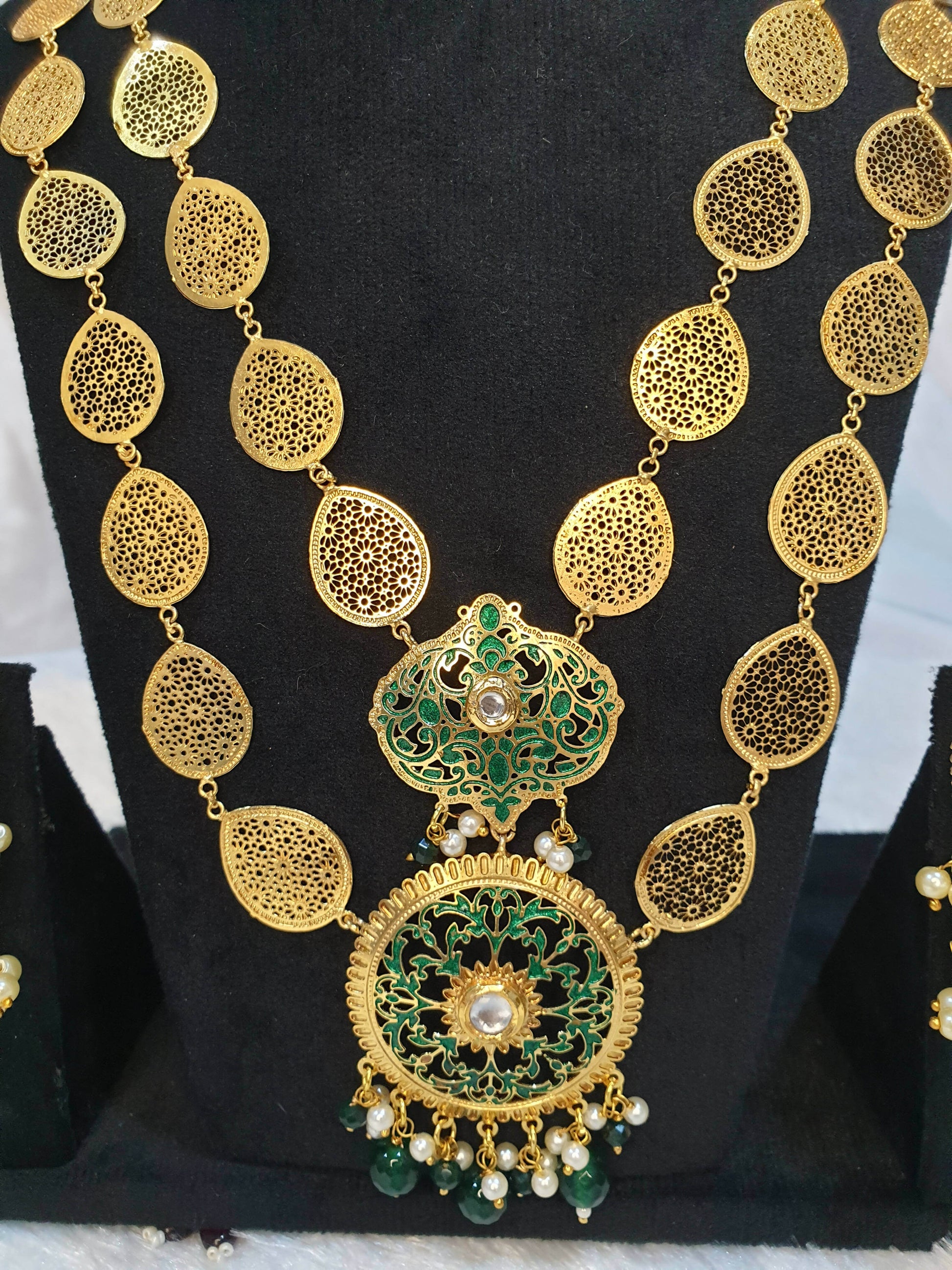A gold-colored double layered filigree petals necklace on the black showpiece.