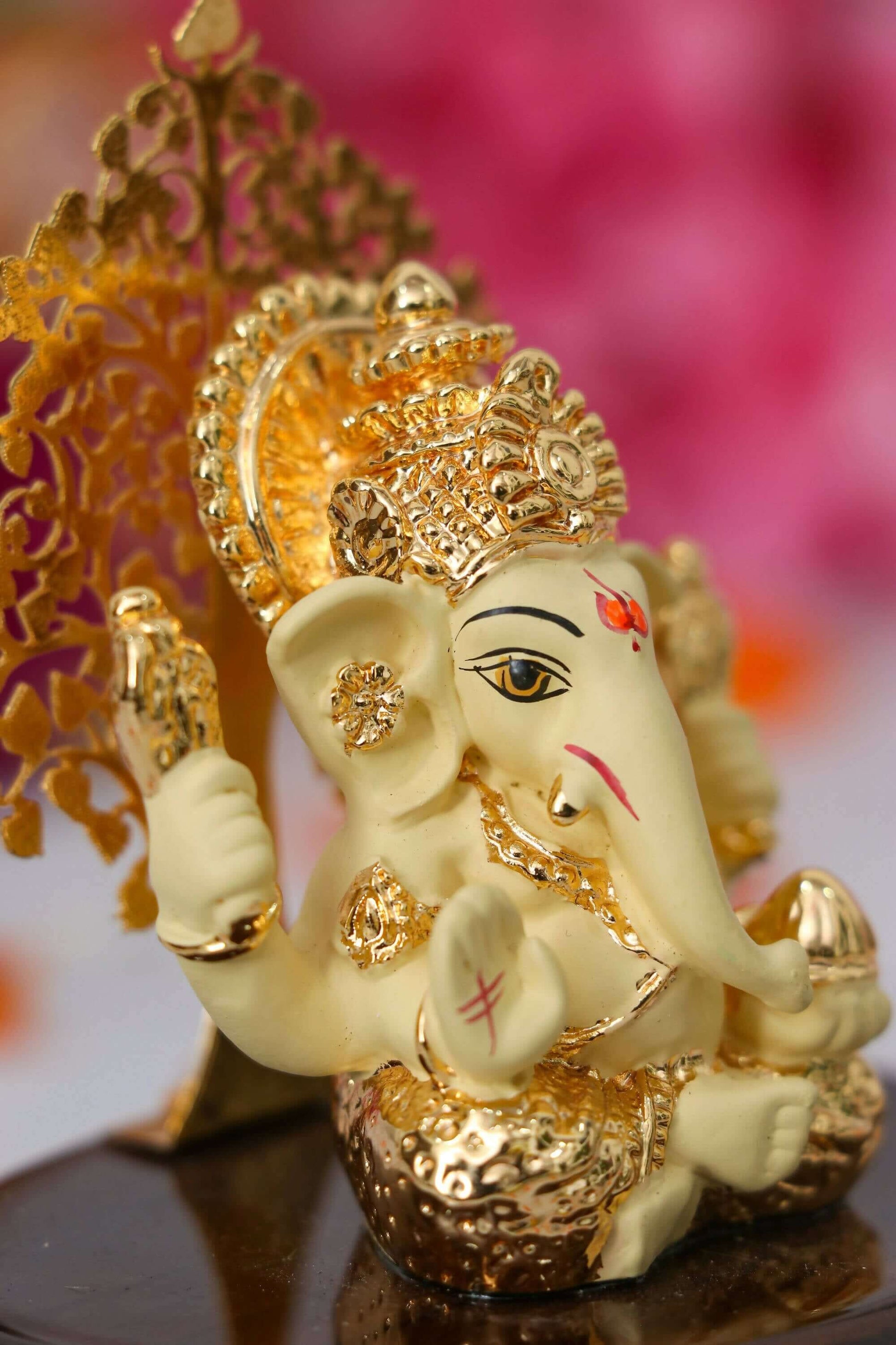 A close-up shot of a golden Ganesha idol, commonly placed on car dashboards, featuring intricate details and a serene expression.