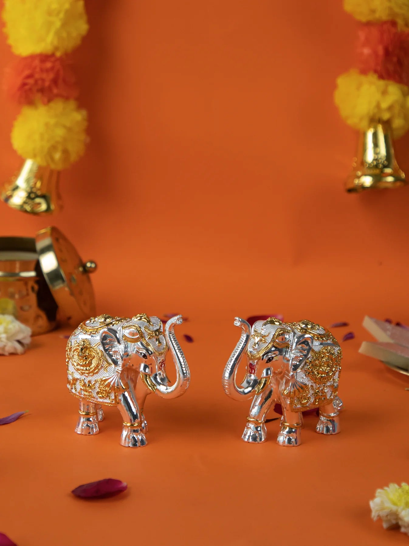 A pair of silver elephant idols with gold-colored detailing, with their trunks raised, used for Vastu, home decor, or gifting.