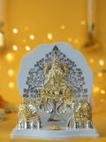 A two-toned Gajalakshmi idol, depicting the goddess Lakshmi seated on a lotus with two elephants flanking her, placed against a yellow background with bokeh lights.