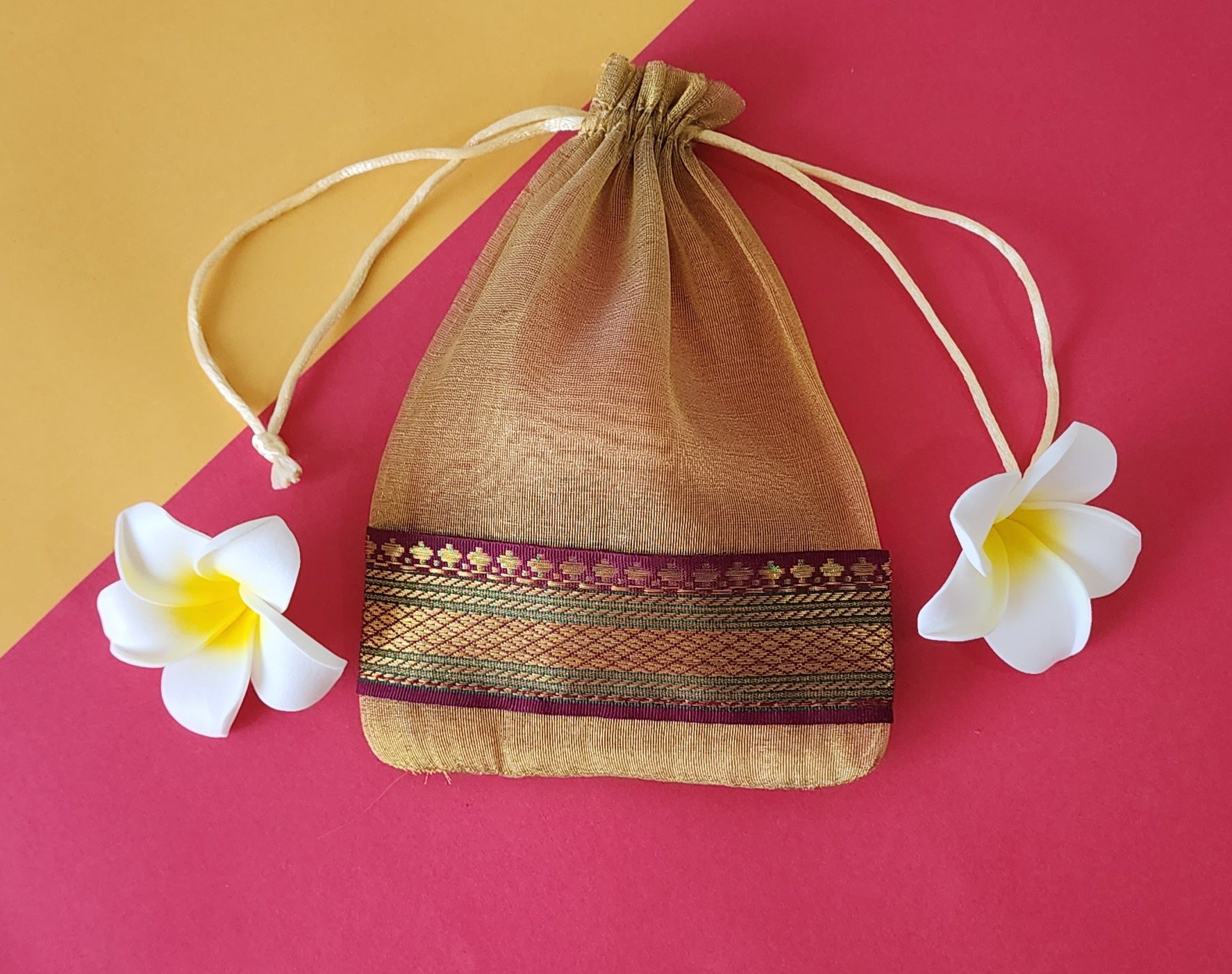 Skin Organza Potli Bags with flowers around it