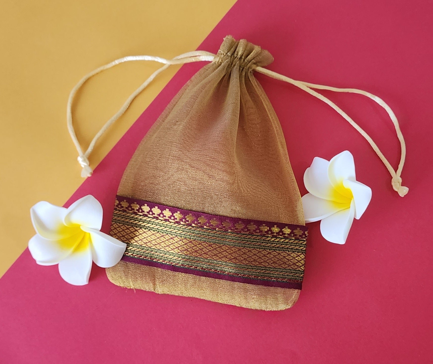 Skin color Organza Potli pouch with flowers around it