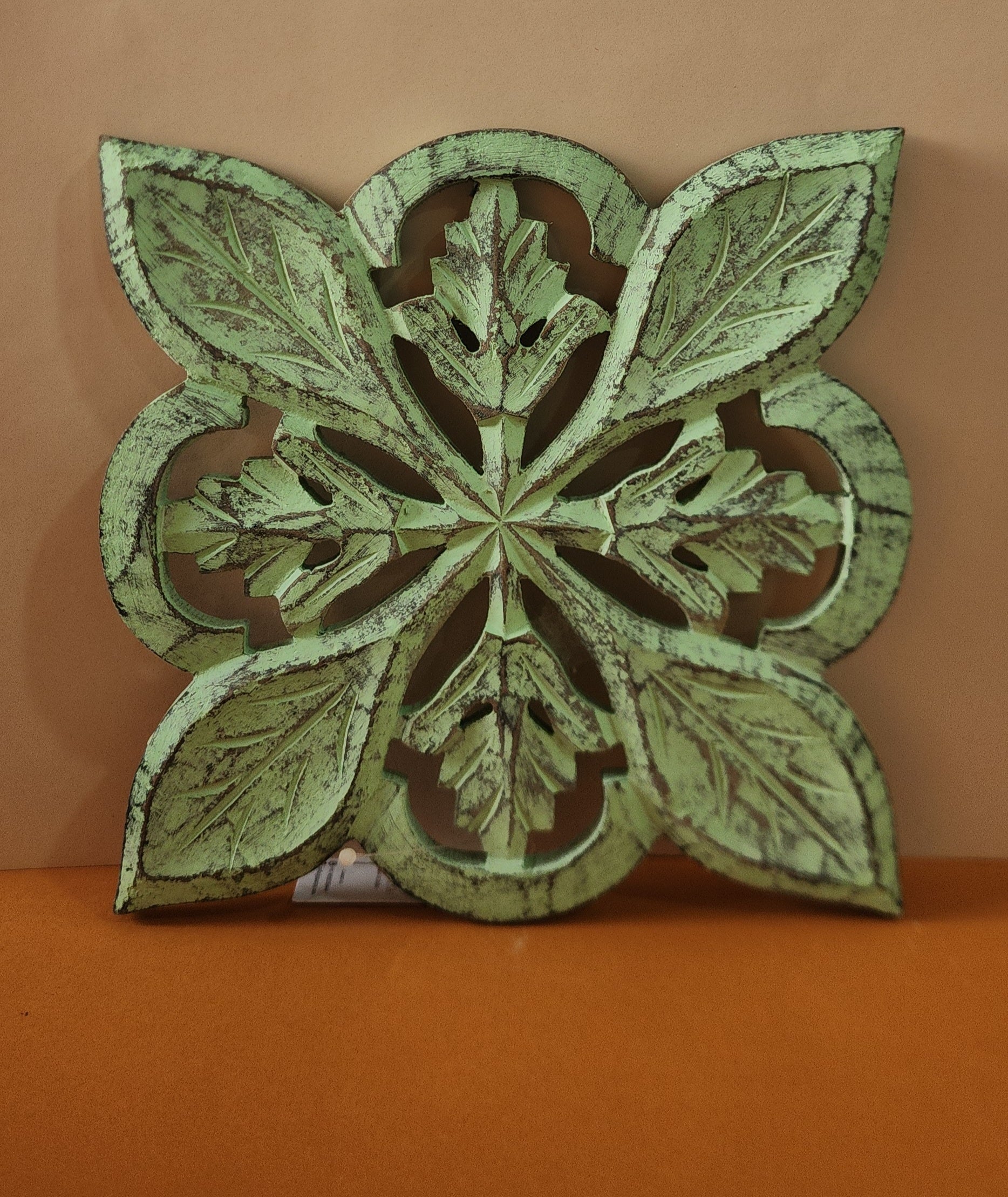 Wooden Carved Trivet in a sleek green finish stand at wall