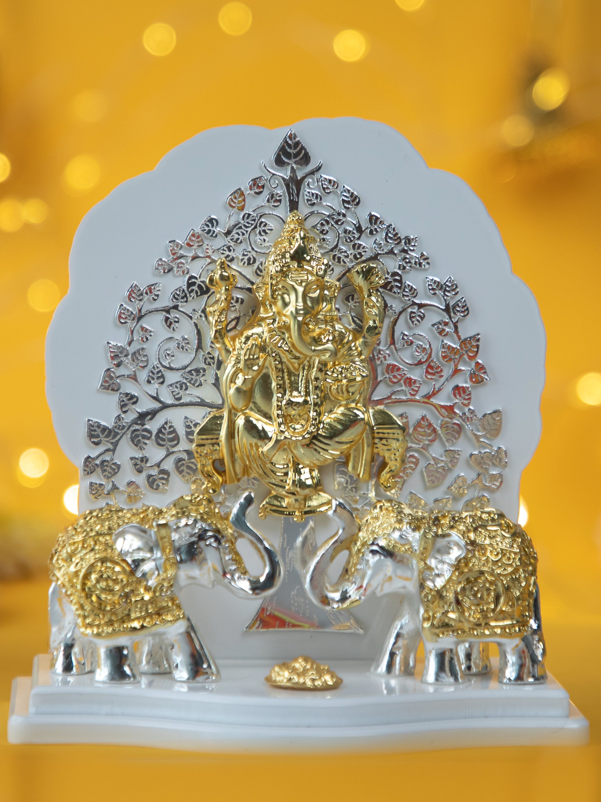 A statue of Ganesha sitting under a Kalpavriksh tree, with two elephants on either side.