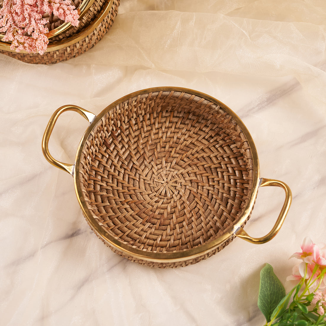 A small round rattan tray with handles, displayed on a neutral background, used for serving or organizing small items.