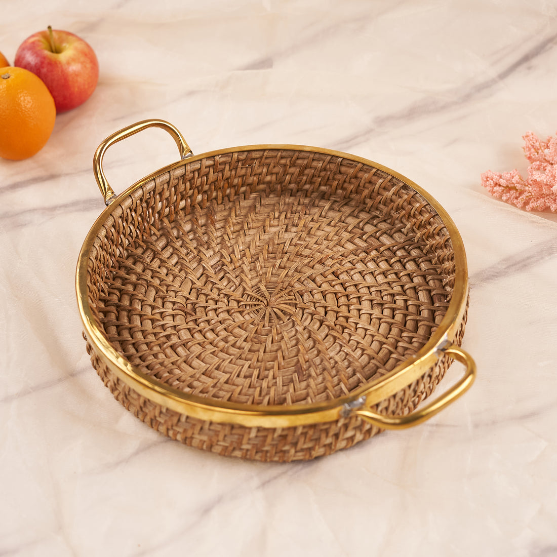A medium-sized round rattan basket with a handle, displayed in a home setting, potentially used for serving or storage.