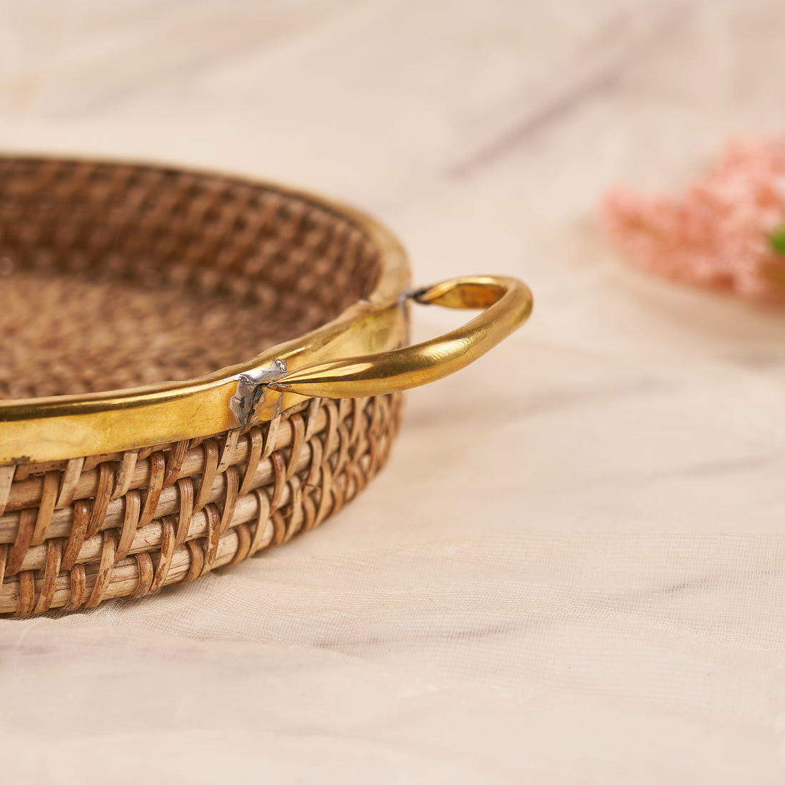 A medium-sized round rattan basket with a handle, displayed in a home setting, potentially used for serving or storage.