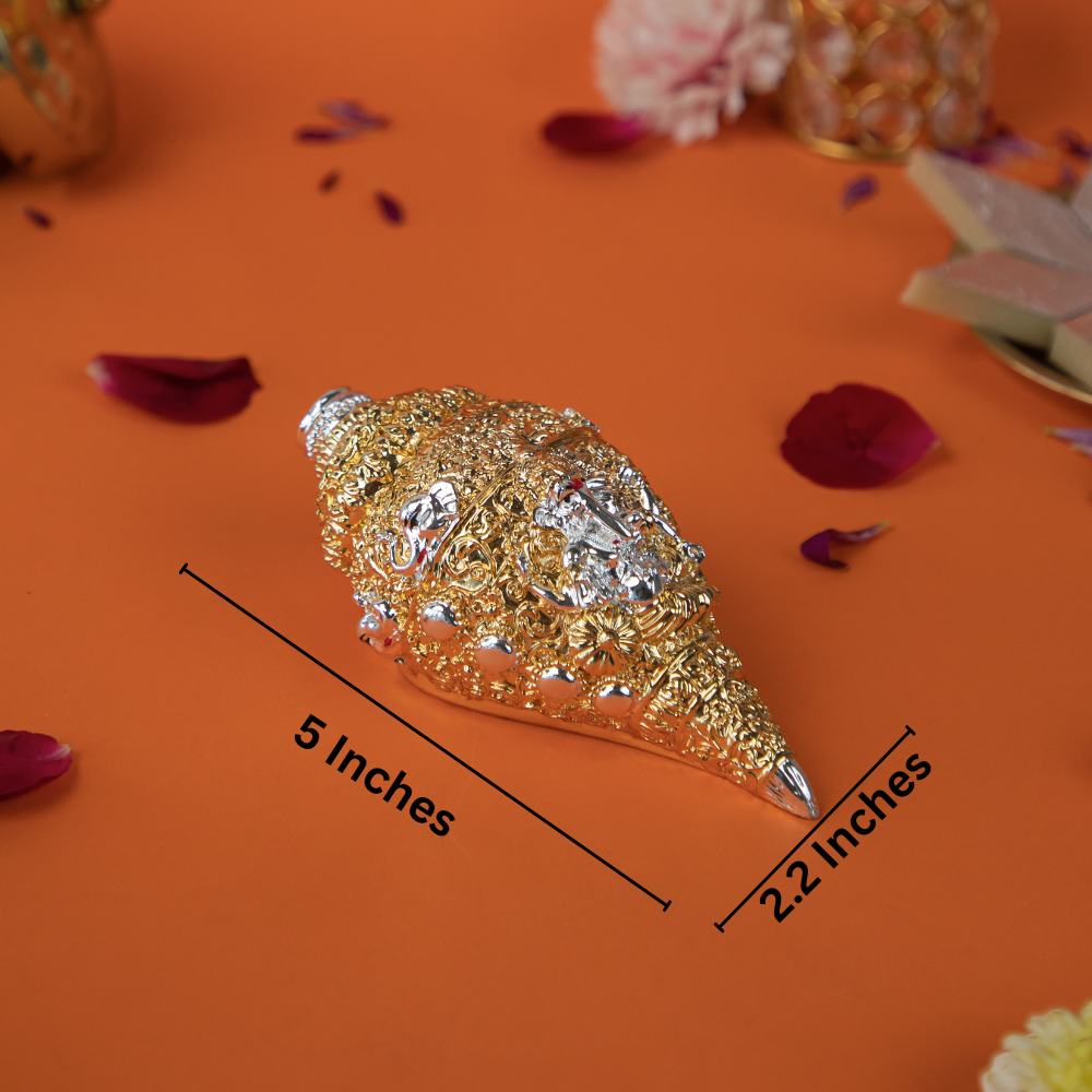 Golden Shankh with the image of Lord Ganesha, measuring 5 inches in length and 2.2 inches in width. The decorative conch shell is embellished with intricate patterns and is displayed on an orange background with flower petals.