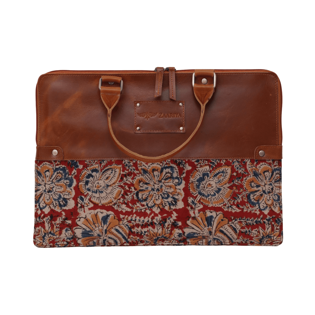 A maroon leather laptop sleeve with a block print pattern on the bottom, placed on a white surface with a patterned fabric behind it.