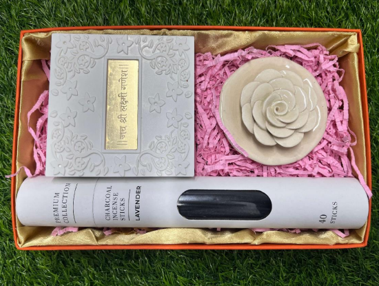 A gift set containing an incense tube, a ceramic rose incense holder, and a Ganesha-Lakshmi pocket temple, all presented in a gift box with a pink interior.